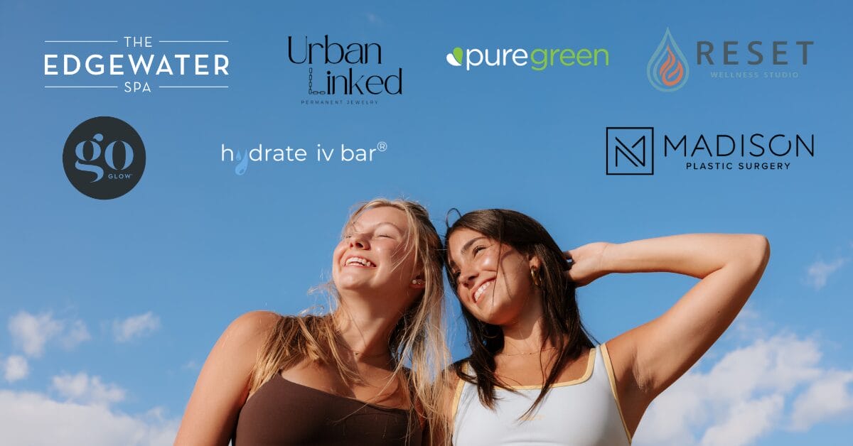 Two smiling women against a blue sky with sponsor logos.